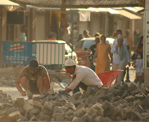Two men sorting through rubble after a disaster