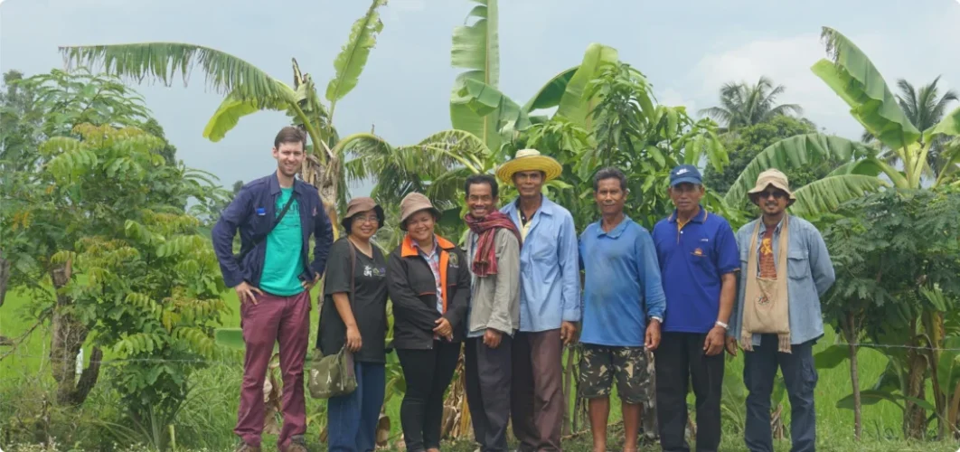 Group posing together in front of banana plants and a green field