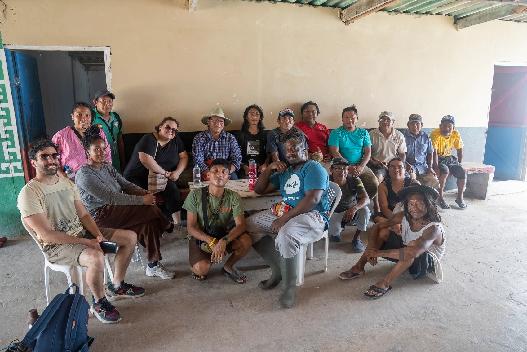 Diverse group posing together indoors around a wooden table in a community space