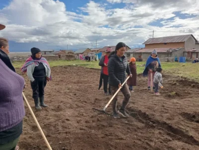 Women and children working a tilled field in a rural highland village