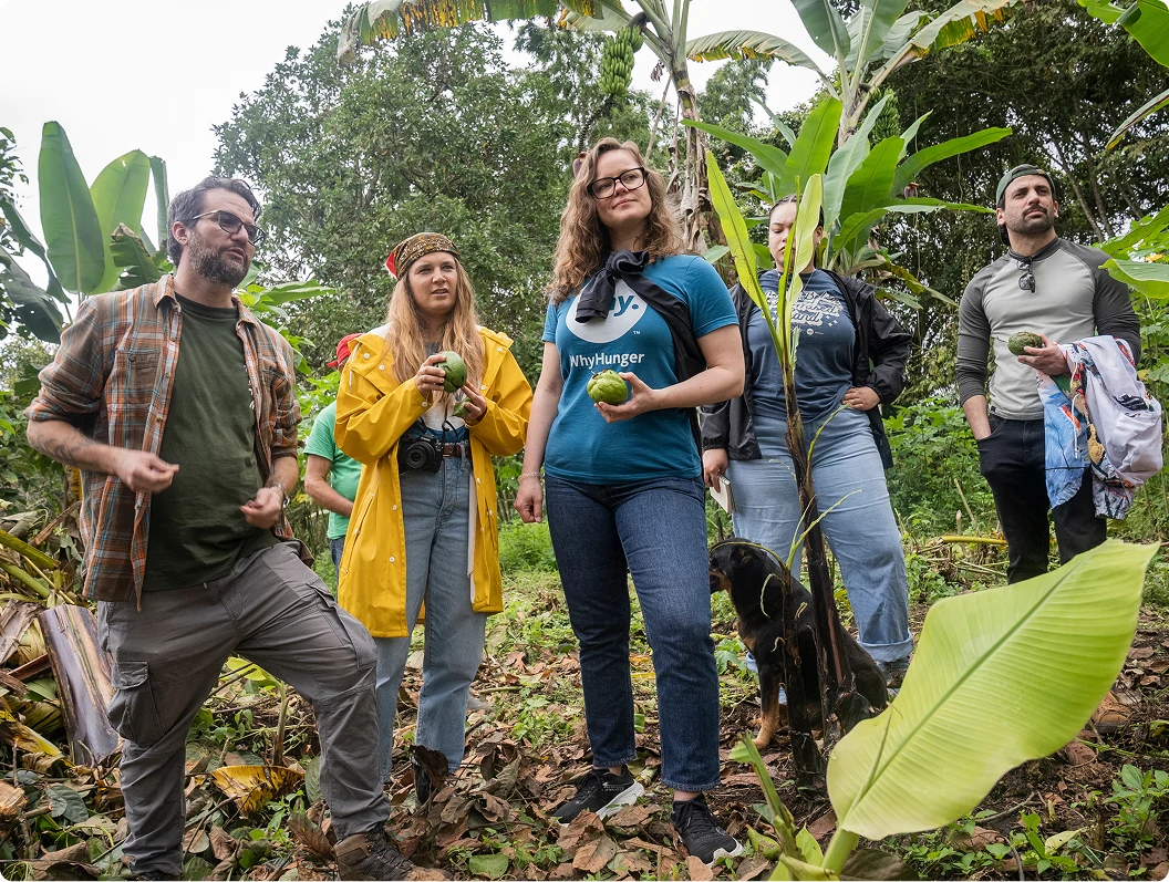 Group holding green fruit during a farm visit among banana trees