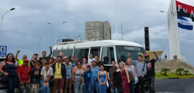 Group raising fists in front of a Fabretto bus beside Nicaraguan and FSLN flags